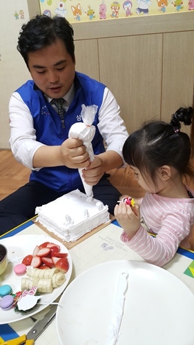 삼성증권 임직원이 결연기관 중 한곳의 어린이와 롤케이크를 만들고 있다.<사진=삼성증권 제공>