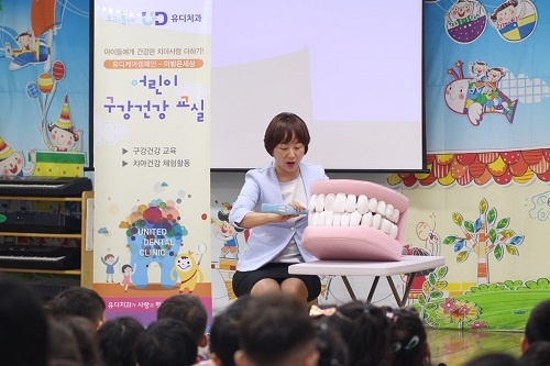 <사진=엔젤어린이집을 방문한 박소양 천안유디신부치과의원 치과위생사가 아이들에게 구강모형을 이용해 올바른 칫솔질 교육을 진행하고 있다, 유디치과 제공>